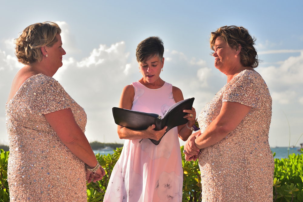 Wedding ceremony with two brides and officiant.
