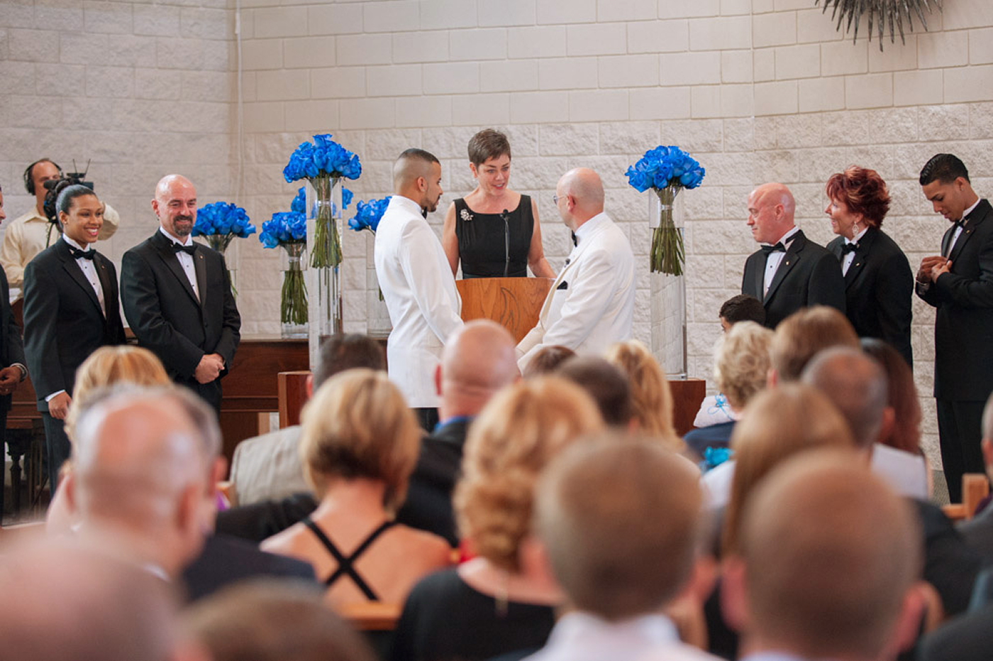 Wedding ceremony with guests and blue flowers.
