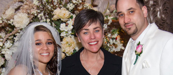 Bride, groom, and woman smiling at wedding.